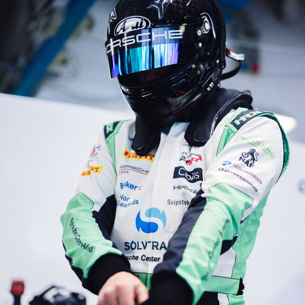 Marius Nakken wearing a Porsche racing helmet and suit preparing for a race.