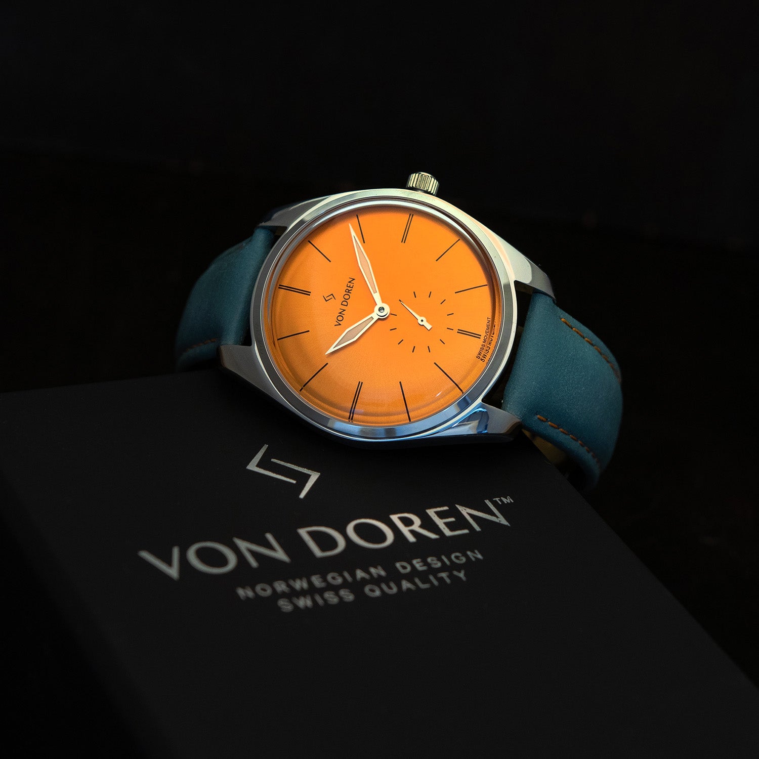 Von Doren klokke. Modell: Runde Warm Yellow sammen med en boks med Von Doren logo.