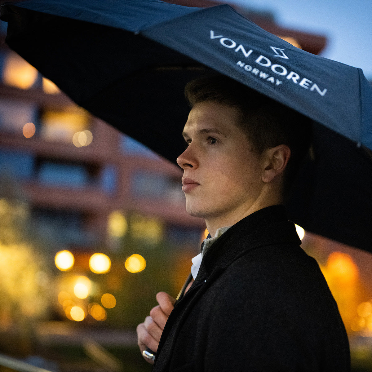 Man holding a Von Doren umbrella on a rainy evening.”