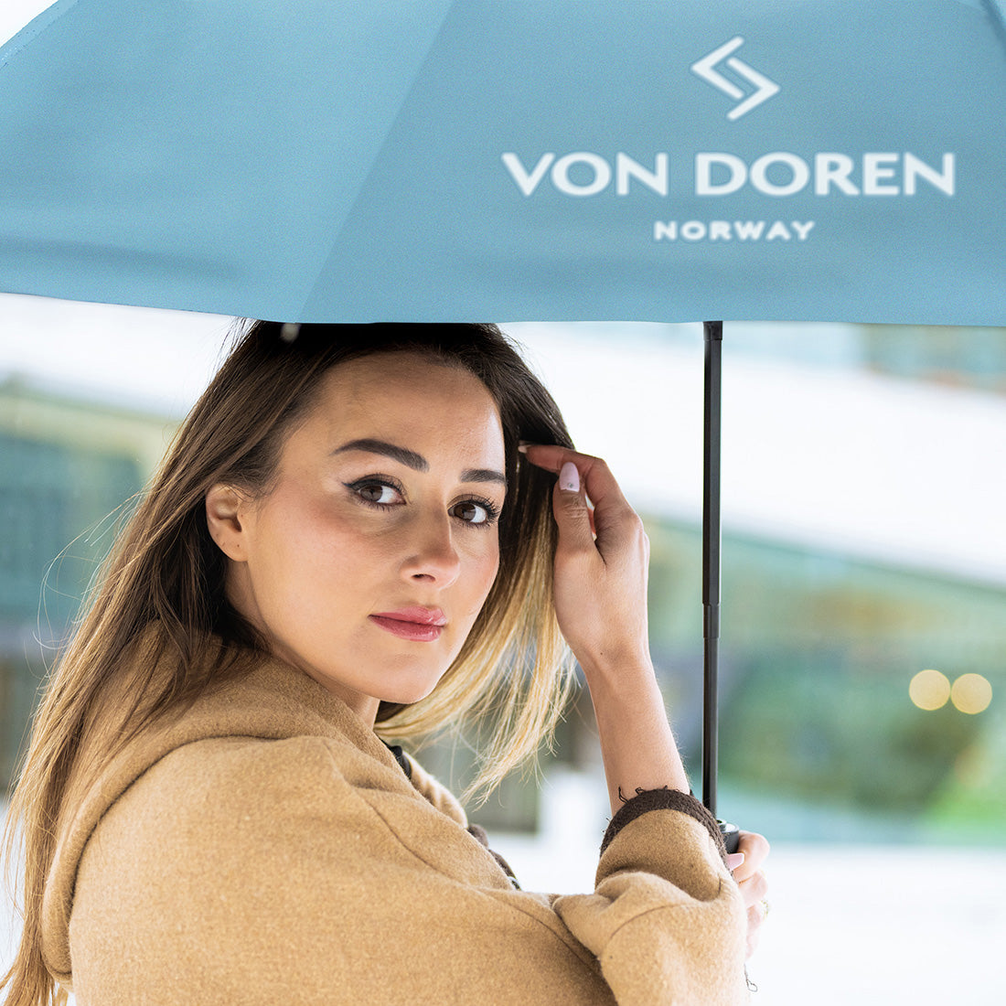 Woman holding a Von Doren Norway umbrella on a rainy day.”